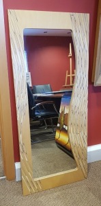 2 X WOODEN ITEMS IE :- 1 X LEICESTERSHIRE WOODEN ART OBLONG WALL MIRROR WITH WAVY EDGE IN CARVED AND DECORATED NATURAL WOOD FRAME 60CM X 140CM PLUS 1 X LEICESTERSHIRE WOODEN ART PANEL ABSTRACT ART VERTICAL LINES IN GROUPS 40CM X 120CM