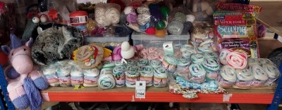 FULL SHELF BRAND NEW MIXED LOT CONTAINING KNITTED UNICORN / DOLL / SCARE CROW PLUSH TOYS / 12 X KNIT SEWING BUMPER PACKS WITH MAGAZINES / VARIOUS COLOURED KNITTING WOOL / 1 X BOX OF DECORATIVE BUTTONS / 1 BOX OFF TEMPLATED FOR KNITTED SWEATSHIRTS / TABLE